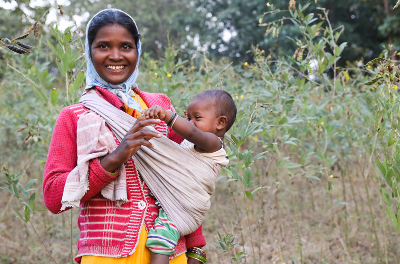 Female farmer standing in a field with her baby