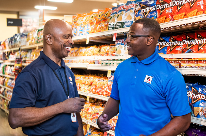 two men standing in front of Frito-Lay chips in a store