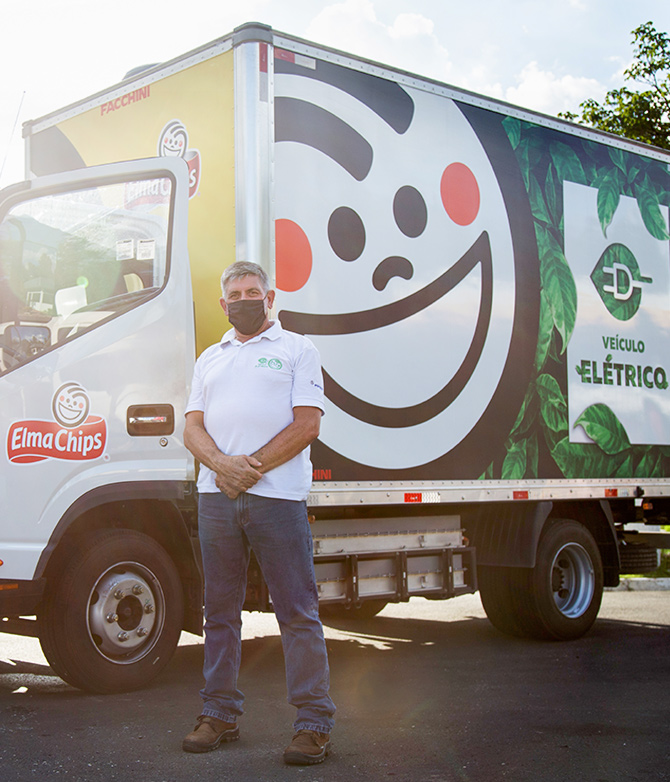 A PepsiCo driver stands proudly in front of his electric powered truck.