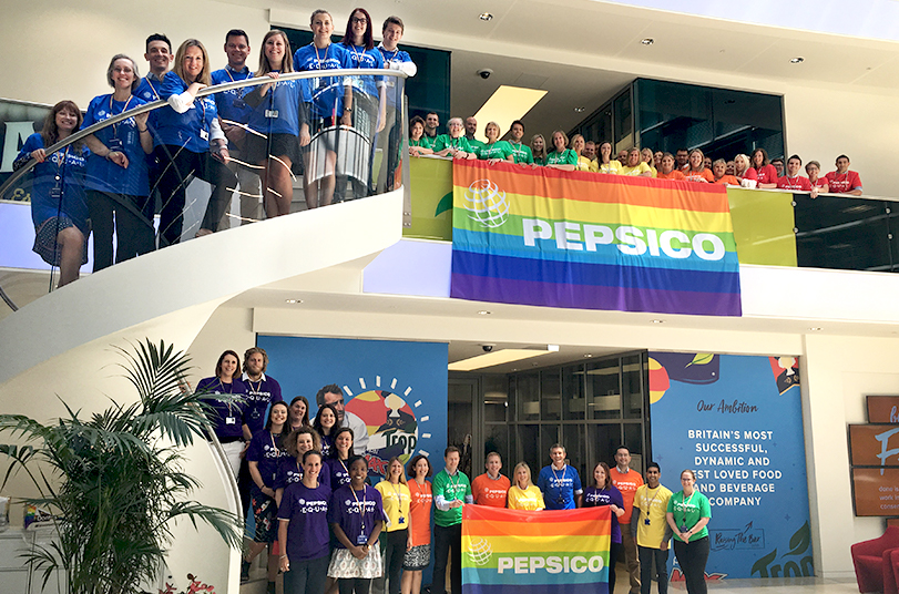 Over 50 people in rainbow Pepsi EQUAL shirts display Pride banners on the ground floor, winding up the stairs, and across the top floor balcony of the building. | LGBTQ